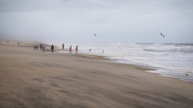 Un grupo de bañistas mira a gente haciendo kitesurf entre las olas provocadas por la tormenta...